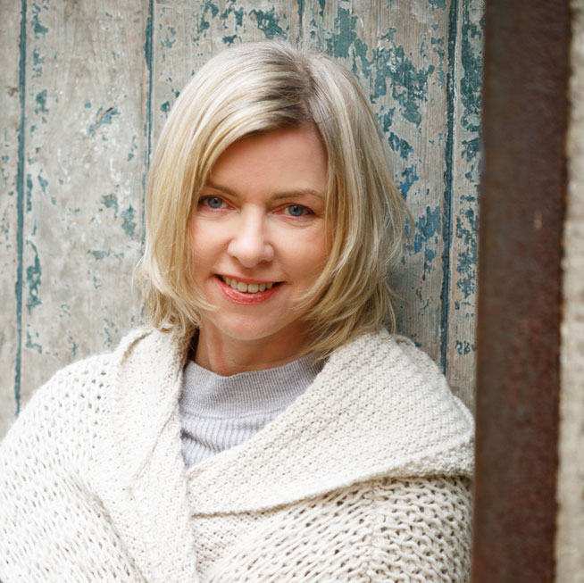 danielle mclaughlin smiles with short blonde hair and white knitted sweater